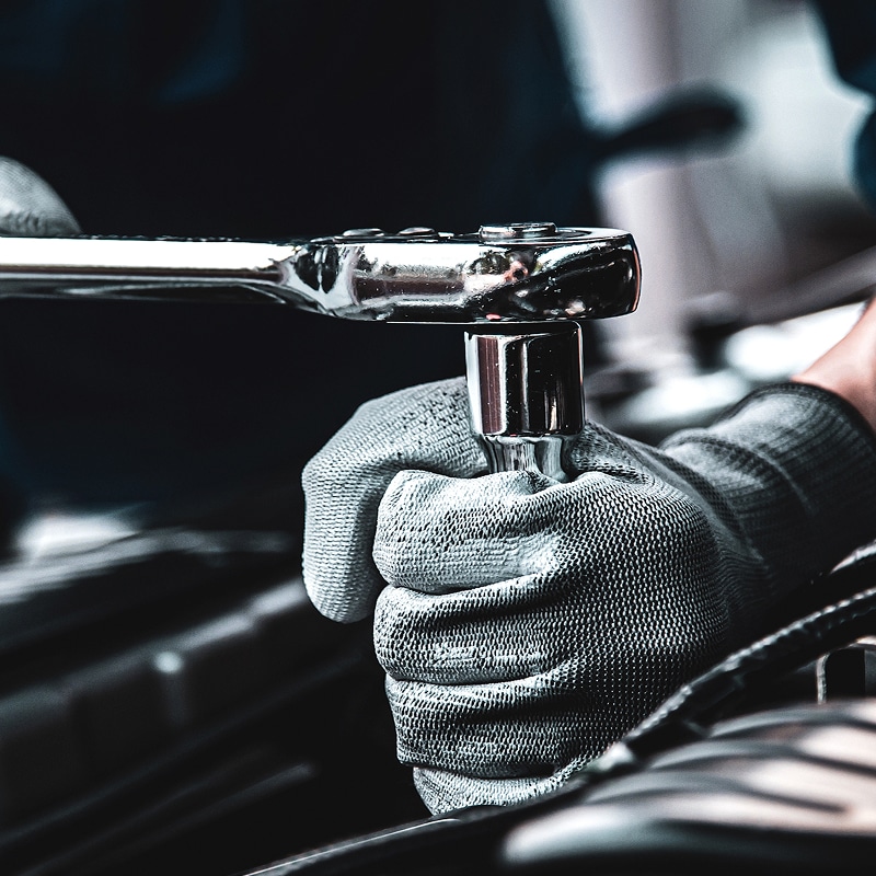 Clé à cliquet : Mécanicien Réparation Auto & Outils Mécanicien ganté ajustant un écrou avec une clé à cliquet chromée, gros plan sur l'outil et la main, travail de réparation automobile.