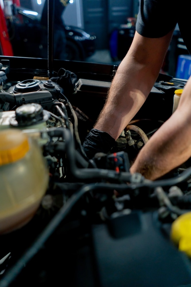 Réparation automobile : Atelier moderne avec véhicules sur ponts Garage automobile moderne et lumineux avec mécaniciens en blouse blanche réparant des véhicules sur des ponts élévateurs rouges, moteur apparent.